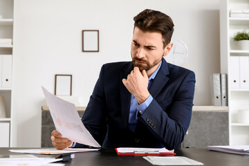 Angry businessman with paper at table in office