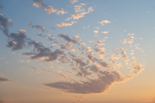 Early evening sky with fresh air and freedom, white fluffy clouds in blue sky with hint of yellow sun rays, as a nature background
