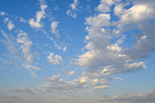 Early evening sky with fresh air and freedom, white fluffy clouds in blue sky with hint of yellow sun rays, as a nature background
 - Powered by Adobe