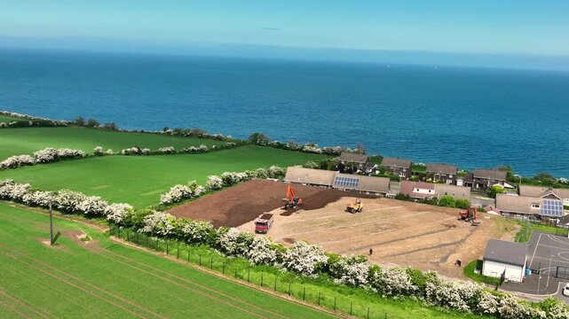 Slow motion aerial view of machinery at construction of sports fields Corran Integrated Primary School Larne N. Ireland 10-02-2025