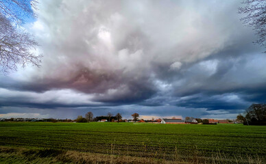 Fototapeta premium Dark and ominous clouds loom above vibrant, lush fields, perfectly capturing the essence of serene rural tranquility