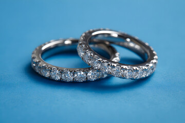 Close-up of diamond eternity rings on a blue background, highlighting their elegance and intricate craftsmanship.