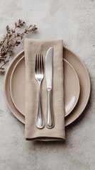Elegant Table Setting with Beige Plate Silverware and Textured Napkin on Speckled Gray Surface Overhead View