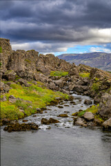 Thingvellir National Park drowning pool Clear pond and stream at the base of a towering tectonic cliff