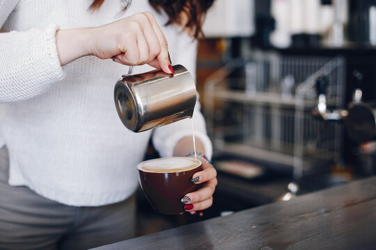 Overhead view female barista pouring milk foam into cappuchino in cafe - Powered by Adobe