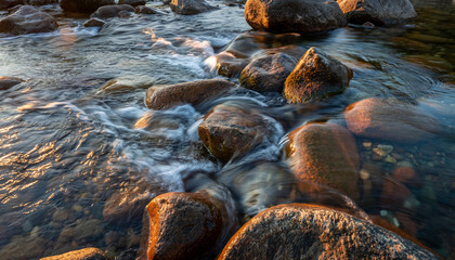 Sunlit River Rocks A Serene Waterway Scene.