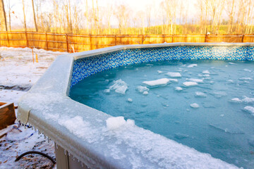 Chilly winter morning shows an above ground pool partially frozen with ice chunks floating.