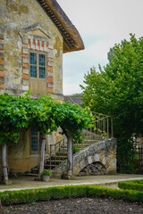 The Hameau de la Reine at Trianon, Marie Antoinette’s pastoral estate with charming rustic cottage buildings, landscaped flower gardens, showcasing  historic elegance and beauty of French countryside