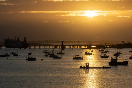 Golden sunrise light reflecting across the water with moored boats