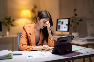 Stressed businesswoman experiencing headache from excessive overtime work