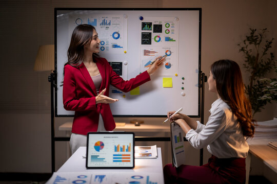 Businesswomen analyzing data charts during late night meeting