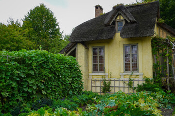 The Hameau de la Reine at Trianon, Marie Antoinette’s pastoral estate with charming rustic cottage buildings, landscaped flower gardens, showcasing  historic elegance and beauty of French countryside © faestock