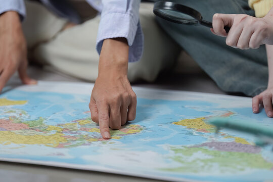 Travel Planning. Friends exploring destinations on a world map with a magnifying glass.