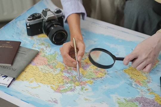 Travel Planning. Two friends exploring destinations on a map with camera and passport.