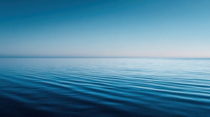 Obraz premium The tranquil ocean stretches endlessly reflecting a gradient of blue hues from the sky. Gentle waves create a peaceful rhythm capturing the essence of twilight.