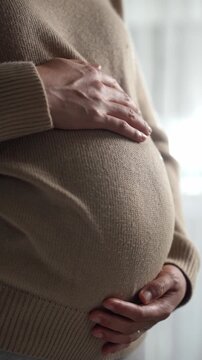 Happy pregnant woman or mother touching baby in belly with love at home. Health care, Prenatal preparation, Maternity, Pregnancy, and motherhood concept