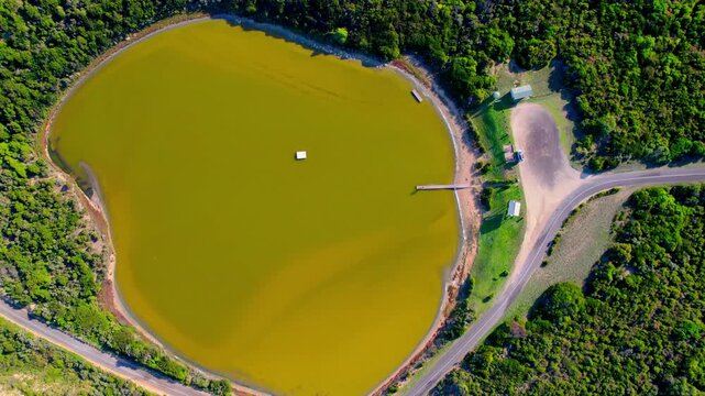 Top-down aerial shot of the yellow Siloam Pool in Beachport, capturing its bright colour, smooth surface patterns and the surrounding natural textures that create a unique coastal saltwater scene.