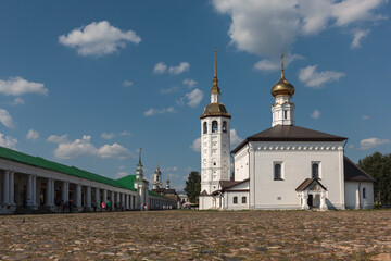 Historic white church and bell tower under blue sky in Suzdal, Russia.