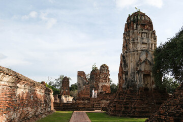 Ancient walkway, Ayutthaya-style pagoda, brick walls and tourists at Wat Mahathat.