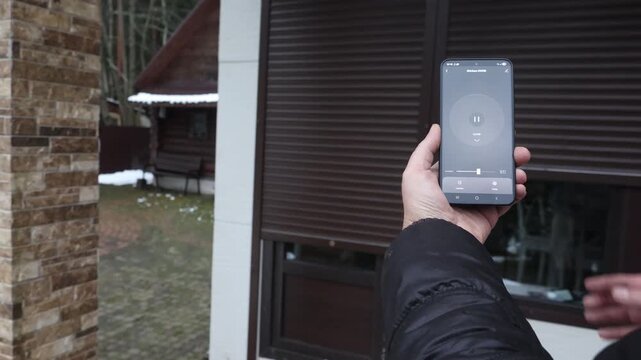 User's hands open door gate and press pause using smart home mobile app, right view. High quality 4k footage
