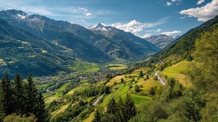 Fototapeta premium A stunning view of a lush green valley nestled between majestic mountains on a bright summer day. The landscape features vibrant fields and scattered trees under a clear blue sky.