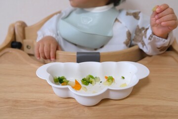 Baby Eating Chopped Vegetables (Weaning Food) in a High Chair (Infant Development and Healthy Eating)