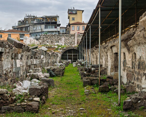 Agora of Smyrna ruins in Izmir, Turkey, with ancient stone walls, a gated archway, and modern...