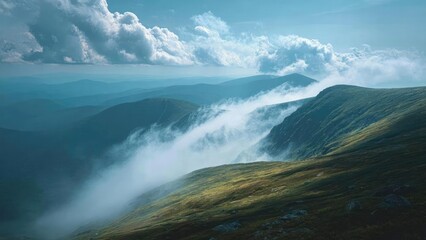Fototapeta premium A ridge of green mountains with mist and clouds sweeping through a valley, distant blue hills fading into the horizon. Concept Misty mountain ridge, Valley fog and clouds, Verdant peaks
