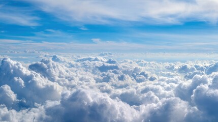 Fluffy white clouds blanket the sky catching sunlight and creating a bright serene atmosphere. The vast expanse of blue is visible in between the clouds giving a feeling of openness.