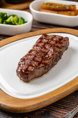 Thick grilled beef steak served on a rustic wooden board