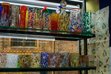 Colorful Murano glass fills the Venice shop window with shimmering patterns. Vibrant shapes reflect artisan skill beside ancient walls. Bright textures create a lively display.