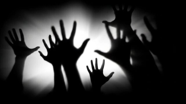 Silhouetted hands reaching up in darkness against bright light