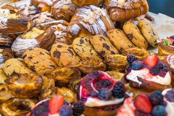 Assorted pastries with cream and fresh berries on the bakery counter. Close-up of sweet desserts. 