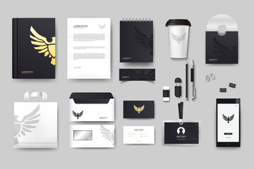 A sleek modern stationery set displayed against a plain backdrop featuring minimalist black and white designs with a golden eagle logo