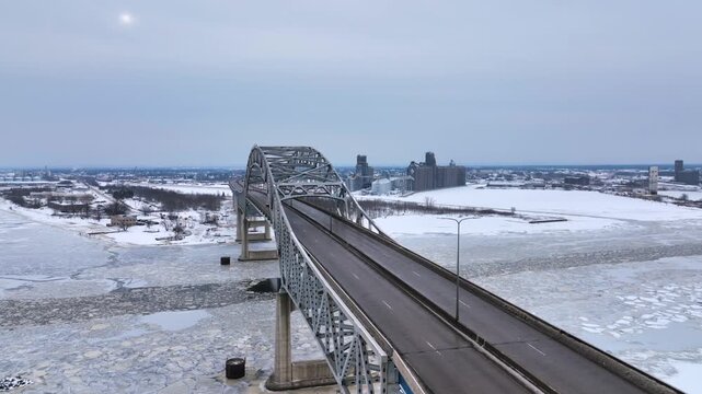 Cars crossing the Blatnik Bridge between Duluth, Minnesota and Superior, Wisconsin across Saint Louis Bay on a gray winter day - Aerial 4K drone video