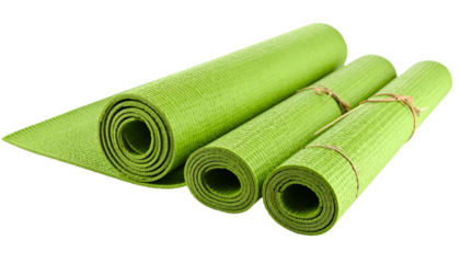Close-up of three green, rolled, textured exercise mats, one unrolled, on black