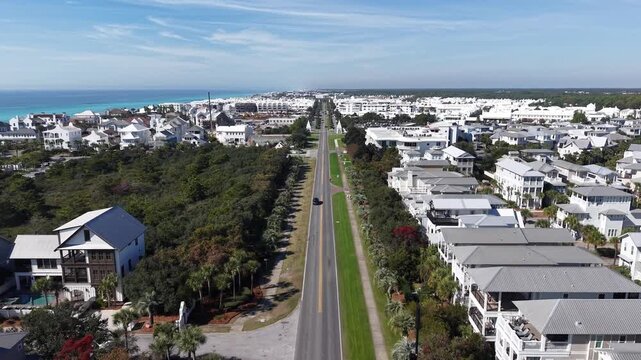 Forward drone fly over long coastal East County Highway 30A road with white houses leading toward near the Gulf at Alys Beach, Florida, USA