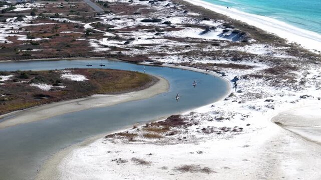 Aerial fly of a winding coastal lagoon meeting white sandy Gulf shoreline, 30A, Florida, USA