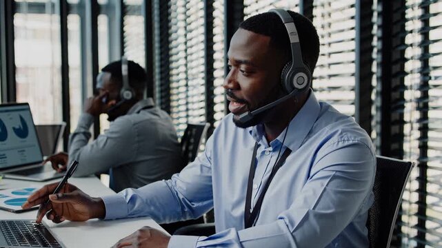 Agent helps customer on call. Service agent speaks with headset and mic. Office team works at laptops and monitors. Support conversation shows focus and collaboration. Professional support