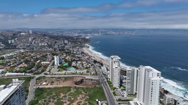 Forward drone aerial of Vi&ntilde;a del Mar coastal high-rise towers, Pacific Ocean beaches, bay panorama, and mountain backdrop, Chile resort city