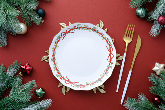 Christmas table arrangement, plate framed by lush, frosted pine branches and ornaments.