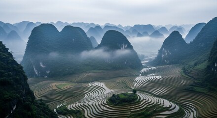 A panoramic view of misty karst mountains and terraced rice fields in a valley.
