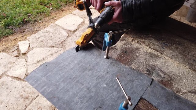 Hands of a tinsmith working with cordless shear accessory for cutting sheet metal mounted on screw diver