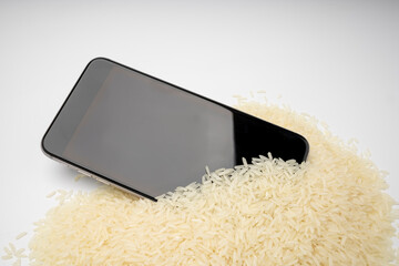 A wet smartphone is dried in rice on white background