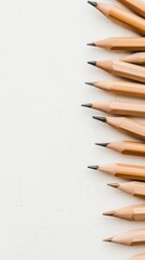 Obraz premium Many sharpened pencils lined up vertically on a textured light background, ready for use.