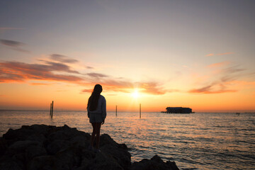 Behind teen girl watching beautiful sunrise Anna Maria Island