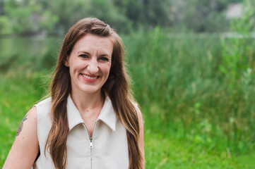 Fototapeta premium Smiling woman standing outdoors in lush green landscape
