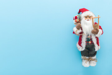 Santa Claus toy on light blue table background. Pastel color. Closeup. Christmas decoration. Empty place for text. Top down view.