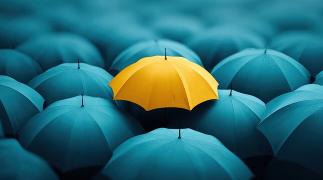 Yellow umbrella stands out among many blue umbrellas, concept of uniqueness