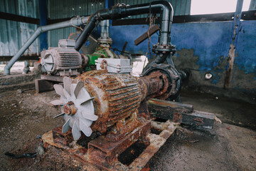 An old, rusty industrial water pump system. Rusty machinery, broken motors, and aging mechanical equipment.
